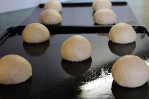 The doughnuts are shaped into balls and left to rise on well oiled baking trays
