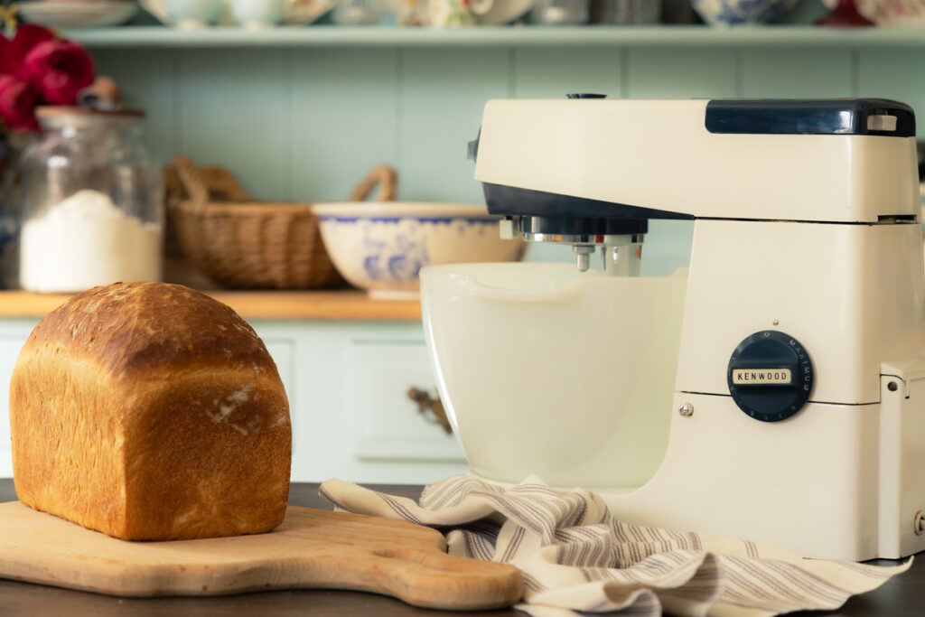 homemade white bread sliced on a bread board with a vintage Kenwood stand mixer