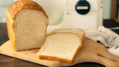 homemade white bread sliced on a bread board with a vintage Kenwood stand mixer