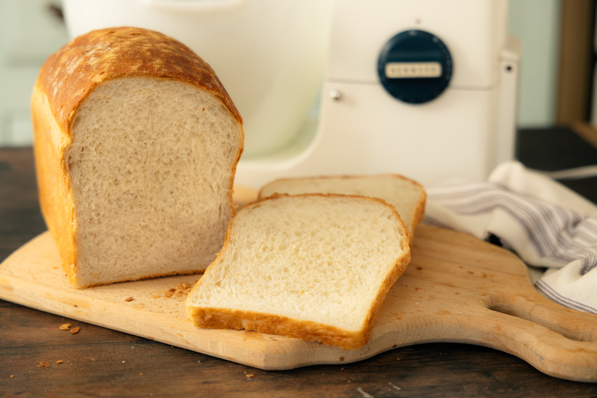 homemade white bread sliced on a bread board with a vintage Kenwood stand mixer