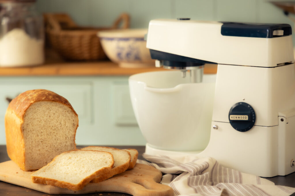 homemade white bread sliced on a bread board with a vintage Kenwood stand mixer