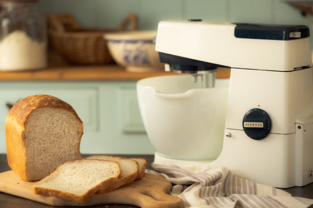 homemade white bread sliced on a bread board with a vintage Kenwood stand mixer