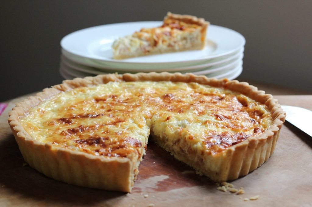 quiche recipe homemade quiche on a wooden board with a slice served on a plate