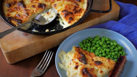cheese potato onion bake portion served with sausage and peas