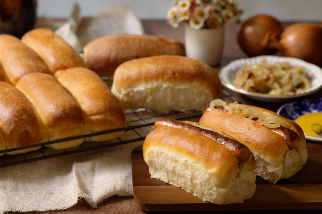 freshly baked homemade hotdog rolls with sausages and fried onions
