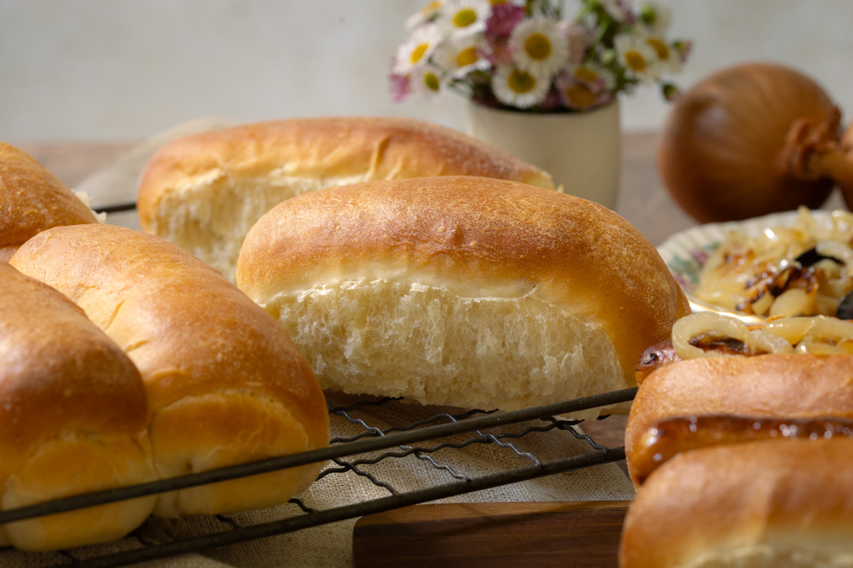 hotdog rolls recipe freshly baked homemade hotdog rolls on a cooling rack and filled with sausages and fried onions