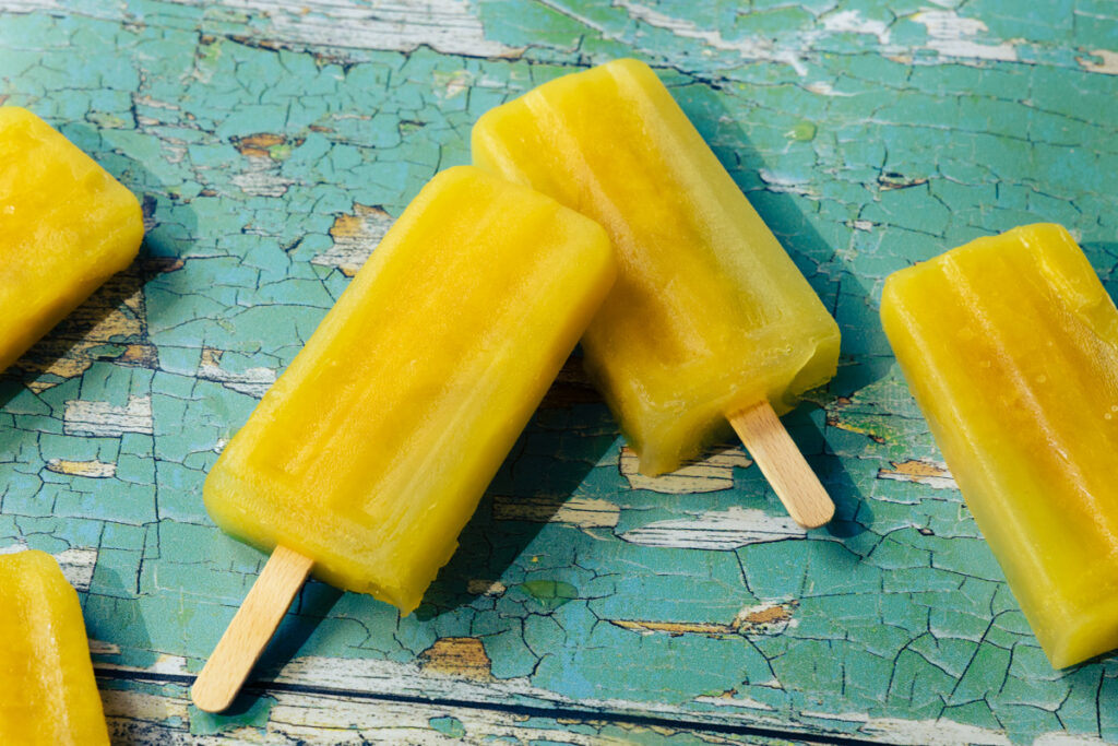 Orange juice ice lollies on a wooden board with old flaking paint